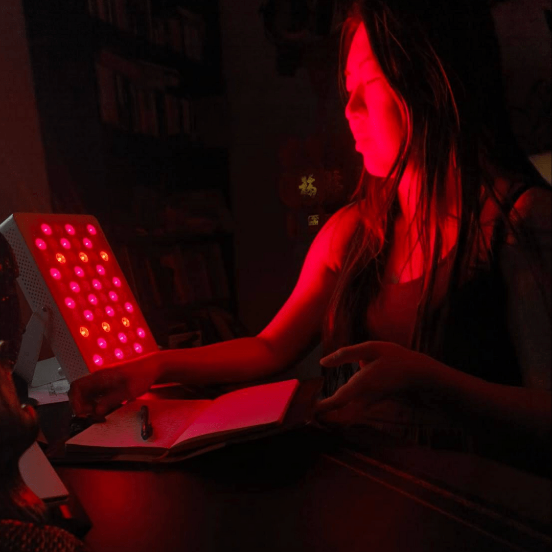 Woman using great value Hero60 tabletop red light therapy panel by Red Light Hero in a dimly lit room