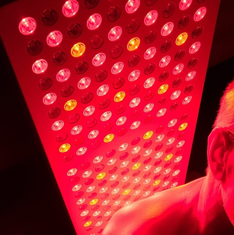 Person sitting in front of a Hero300 red light therapy panel by Red Light Hero