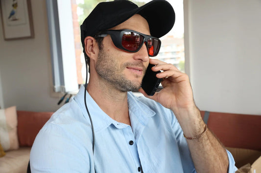 Man wearing the HeroHat LED cap and protective glasses while on the phone