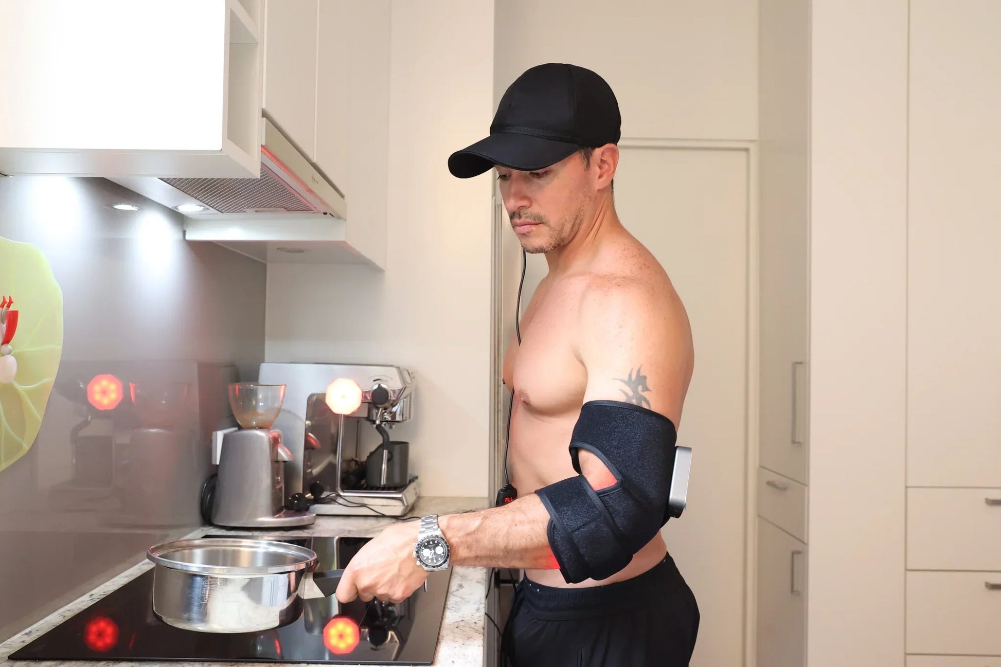Man using a red light therapy arm wrap while cooking
