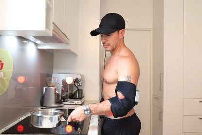 Man using a red light therapy arm wrap while cooking