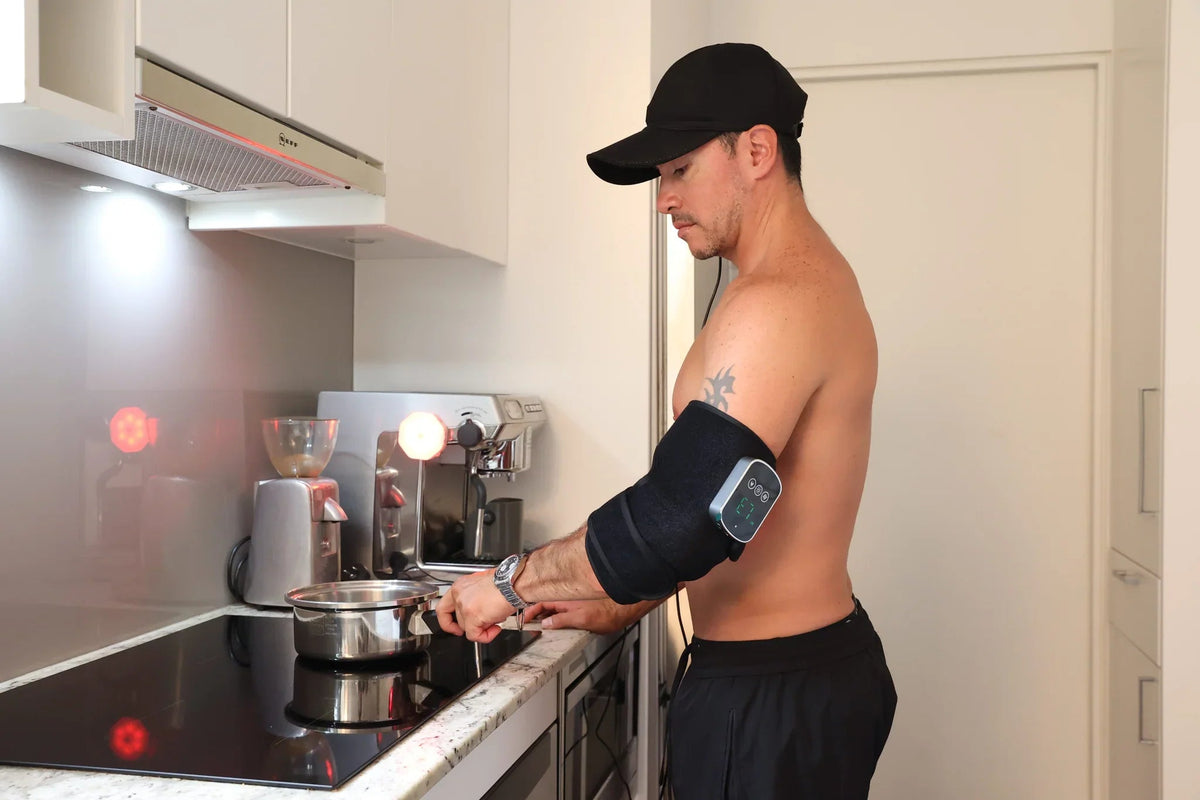 Man wearing a red light therapy arm wrap while cooking