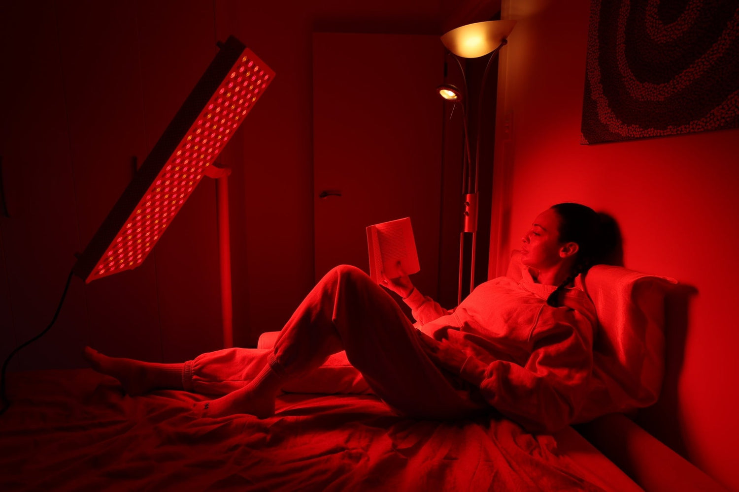 Man reclining beneath an angled overhead red light therapy panel