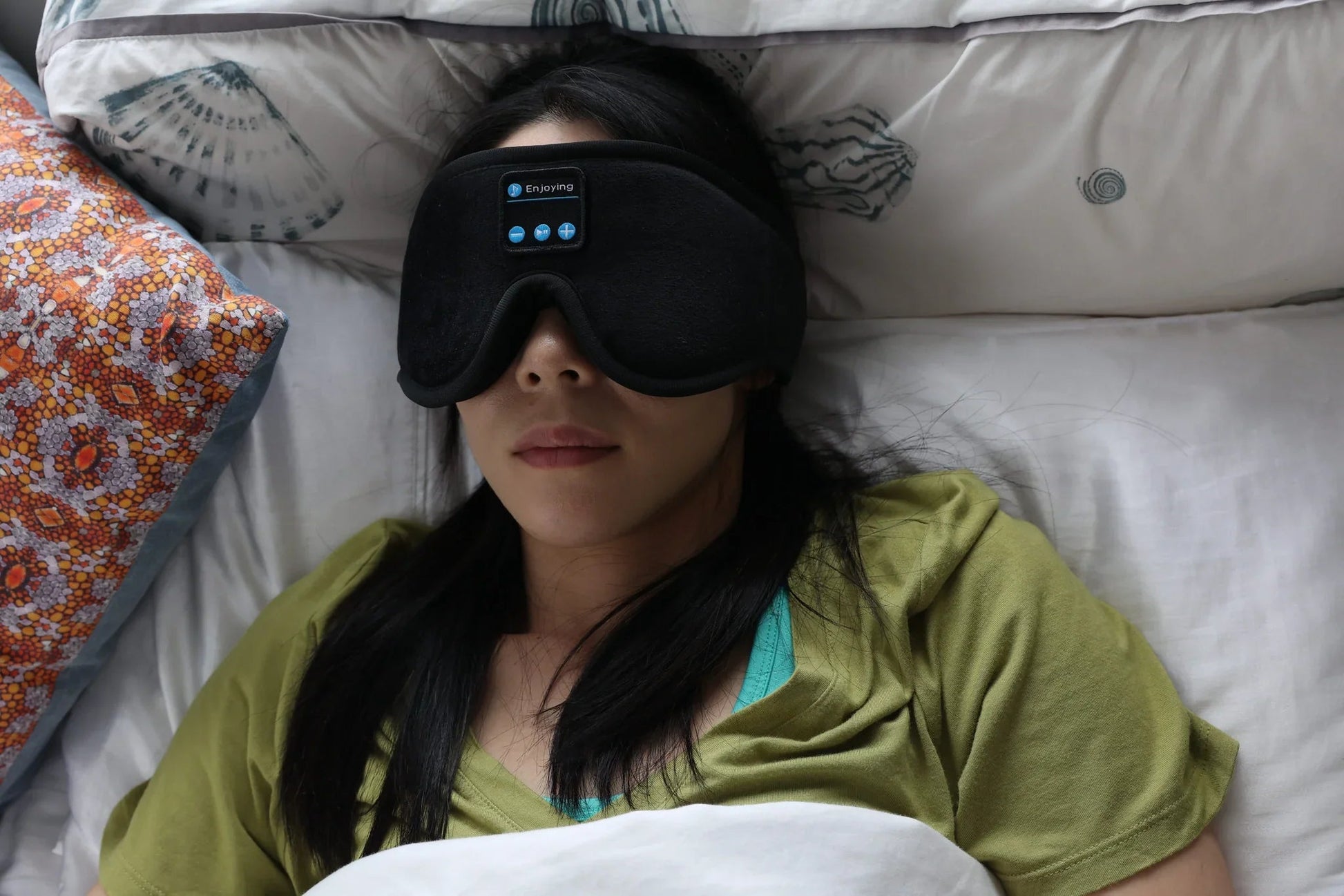 Woman resting in bed with the HeroSleep Soothe mask control panel visible
