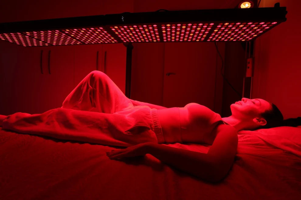 Woman receiving full-body red light therapy beneath an overhead panel system
