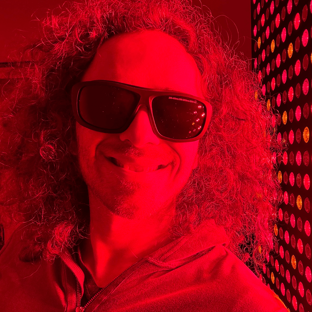Woman wearing wraparound protective glasses beside a red light panel