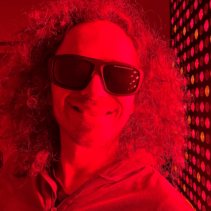 Woman wearing wraparound protective glasses beside a red light panel