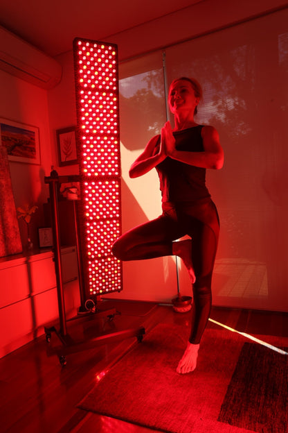 Woman in tree pose beside an illuminated Hero300 panel