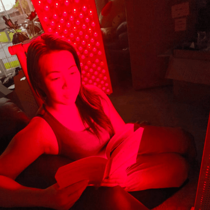 Woman relaxing in red light beside an illuminated Hero300 panel
